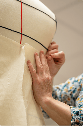 Ajustement manuel d'un tissu sur un mannequin de couture, illustrant le savoir-faire en modélisme